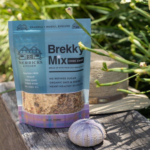 Package of Merricks Kitchen Brekky Mix Choc Chip healthiest chocolate granola on a wooden surface with greenery in the background