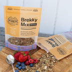 Merricks Kitchen Brekky Mix Original healthy granola packages on a wooden surface with berries and granola.
