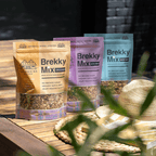 Brekky Mix Variety Pack sitting on outside table with hat and book in forground